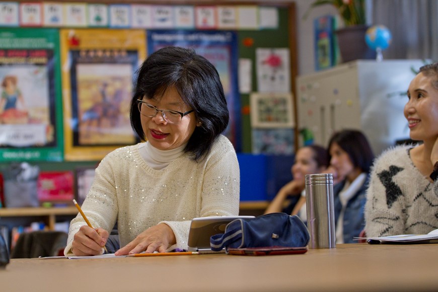 ESL learner in a classroom writing in a notebook